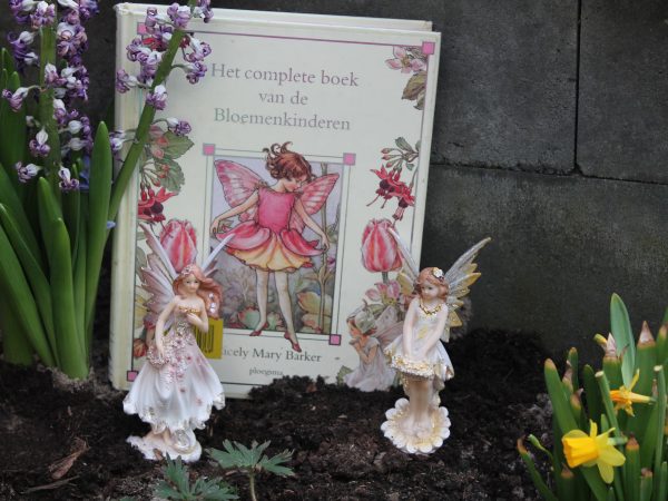 Bloemenkinderen in tuin met beeldjes