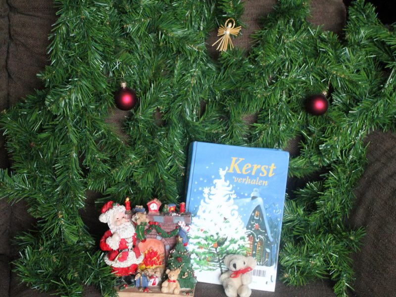 Boek kerstverhalen, tak kerstboom, kerstballen, kerstman bij open haard